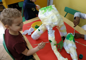 Dzieci podczas malowania dinozaura